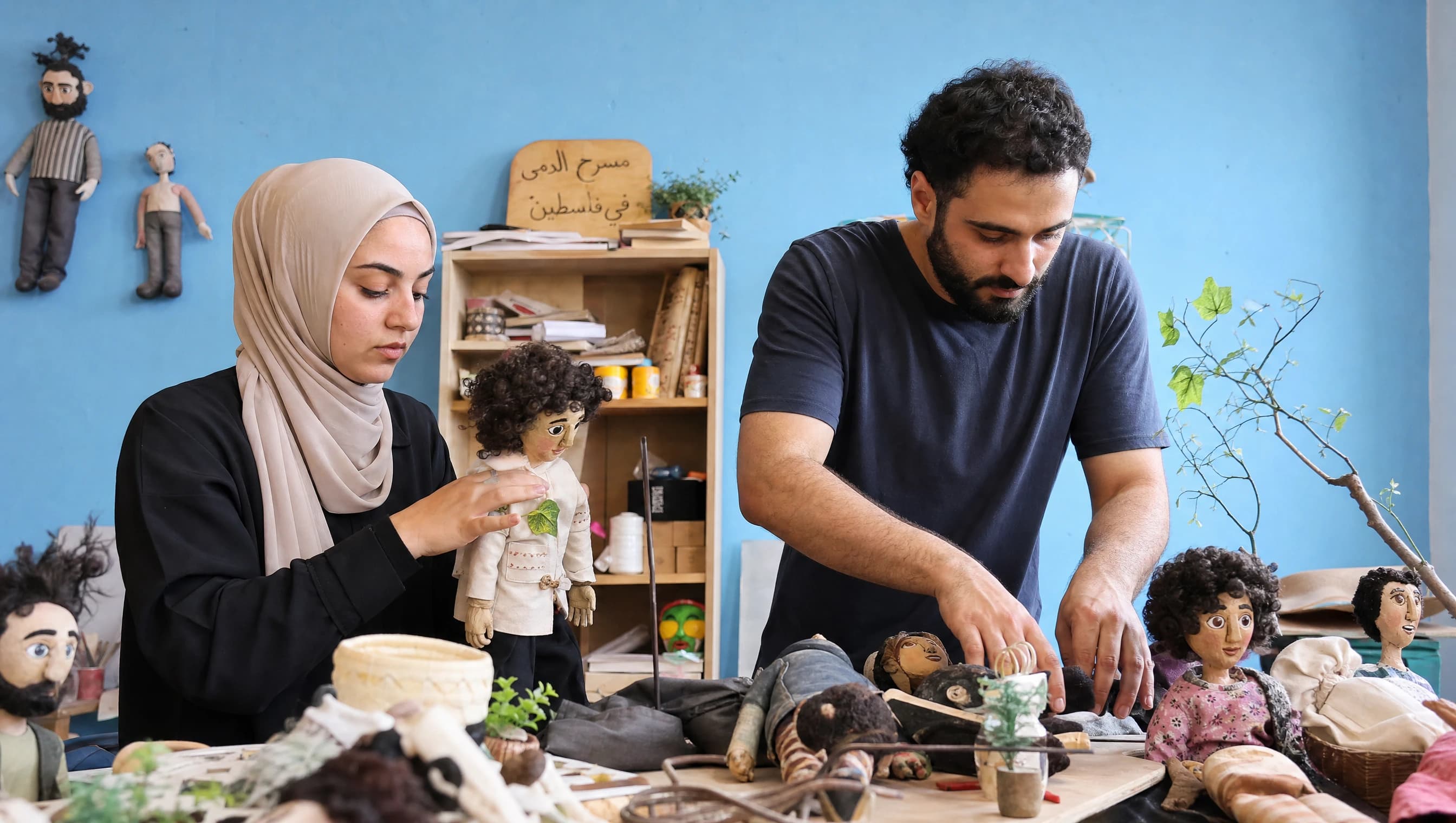 اثنان من الفريق يجهّزان دمى مسرح الدمى على طاولة العمل